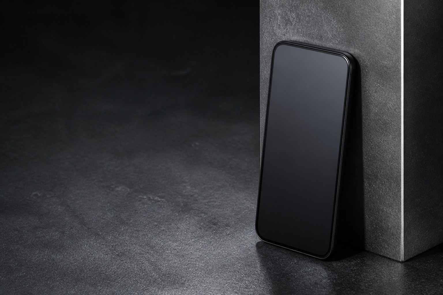 An iPhone resting against a machined graphite column, lit from the side.